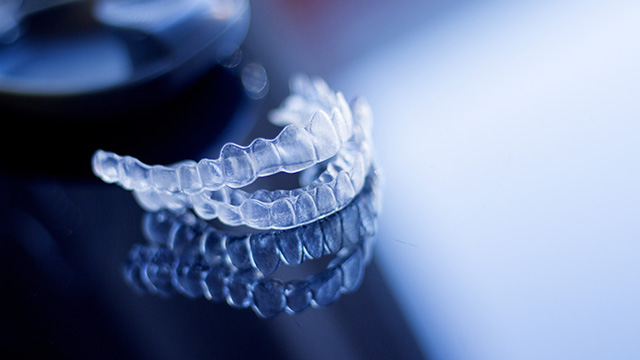 An image of a transparent, tooth-like object with a spiral pattern, possibly a dental implant or a model for dental education.